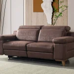 A modern multi-seater recliner sofa featuring adjustable headrests, extendable footrests, wide plush armrests, and a rich textured leatherette finish in a contemporary living room setting.
