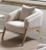 Velora Armchair featuring a curved barrel-style silhouette, patterned outer upholstery, and angled wooden legs.