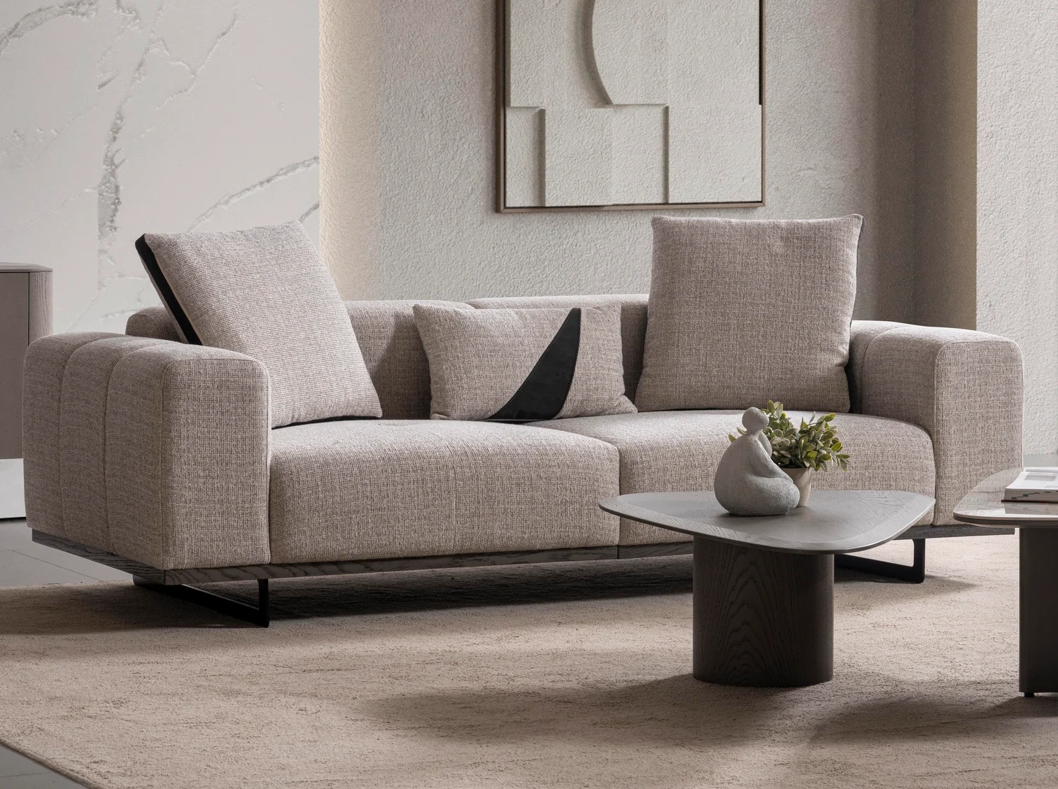 nova-sofa-03 A modern textured fabric Nova Sofa featuring deep seating cushions, adjustable plush backrest pillows, channel-tufted wide armrests, and sleek low-profile metal legs in a minimalist room interior.