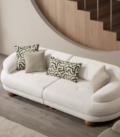 Premium sand grey curved sofa with sculptural round wooden legs and decorative cushions