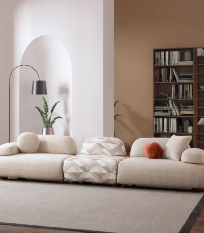 Alba XL Sofa Set featuring a large cream bouclé sectional, a matching loveseat, and a geometric patterned accent chair. The set is arranged in a spacious, modern room with high ceilings, an arched alcove, and a large library bookshelf.