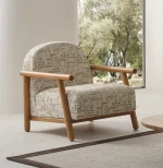 The organic Areon Armchair featuring textured fabric and wooden legs, placed in a bright, minimalist living room that evokes a sense of natural harmony and peace.