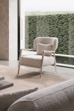 Cora Armchair with an exposed wooden frame and softly curved backrest.