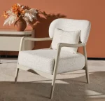 Cora Armchair with an exposed wooden frame and softly curved backrest.