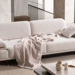 Cora Sofa styled in a modern interior setting with curved armrests and a wide seating surface.