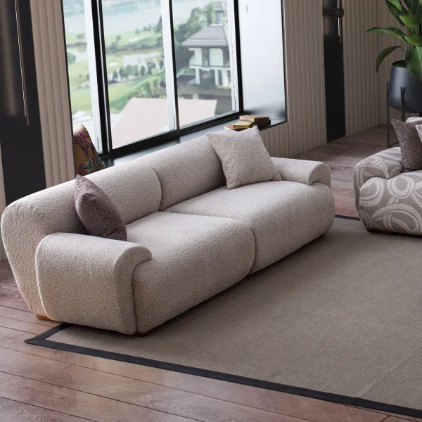 The Elegante Sofa set featuring a plush grey bouclé sofa with rounded arms, a matching L-shaped sectional with patterned accent sections, and a dark brown textured armchair in a luxury room.