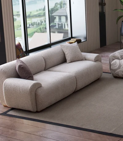 The Elegante Sofa set featuring a plush grey bouclé sofa with rounded arms, a matching L-shaped sectional with patterned accent sections, and a dark brown textured armchair in a luxury room.