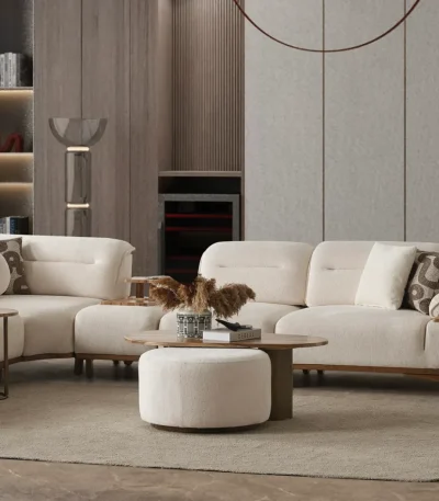 A modern living room featuring the Grace Sofa. The arrangement displays a plush taupe sofa and a matching cream sofa, both designed with distinctive integrated wooden side tables on the armrests and angled wooden legs. A white swivel armchair and a round wooden coffee table complete the cozy, contemporary look of this furniture from Turkey.