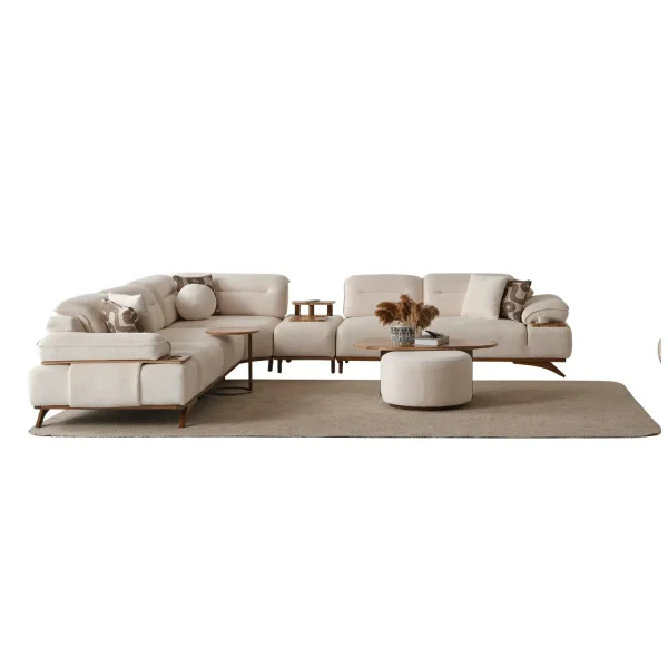 A modern living room featuring the Grace Sofa. The arrangement displays a plush taupe sofa and a matching cream sofa, both designed with distinctive integrated wooden side tables on the armrests and angled wooden legs. A white swivel armchair and a round wooden coffee table complete the cozy, contemporary look of this furniture from Turkey.