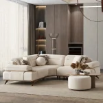 A modern living room featuring the Grace Sofa. The arrangement displays a plush taupe sofa and a matching cream sofa, both designed with distinctive integrated wooden side tables on the armrests and angled wooden legs. A white swivel armchair and a round wooden coffee table complete the cozy, contemporary look of this furniture from Turkey.