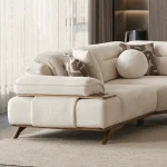 A modern living room featuring the Grace Sofa. The arrangement displays a plush taupe sofa and a matching cream sofa, both designed with distinctive integrated wooden side tables on the armrests and angled wooden legs. A white swivel armchair and a round wooden coffee table complete the cozy, contemporary look of this furniture from Turkey.