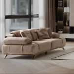 A modern living room featuring the Grace Sofa. The arrangement displays a plush taupe sofa and a matching cream sofa, both designed with distinctive integrated wooden side tables on the armrests and angled wooden legs. A white swivel armchair and a round wooden coffee table complete the cozy, contemporary look of this furniture from Turkey.