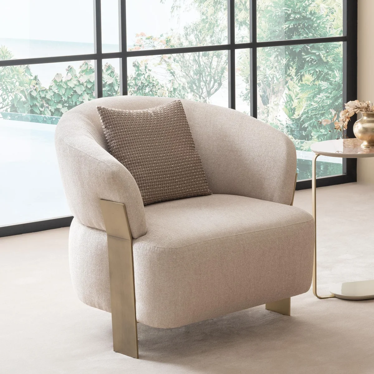 A luxurious modular Grandeur sofa set in a bright, modern living room. The set features cream-colored fabric upholstery with rectangular cushions and sleek gold metallic legs. Beside the modular sections sits a matching rounded armchair with gold accents. The scene includes minimalist decor, a marble coffee table, and large windows, highlighting the elegant design of the Grandeur furniture from Turkey.