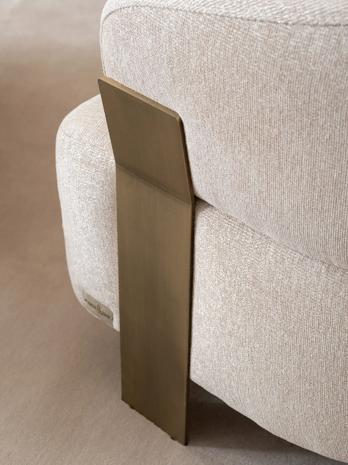 A luxurious modular Grandeur sofa set in a bright, modern living room. The set features cream-colored fabric upholstery with rectangular cushions and sleek gold metallic legs. Beside the modular sections sits a matching rounded armchair with gold accents. The scene includes minimalist decor, a marble coffee table, and large windows, highlighting the elegant design of the Grandeur furniture from Turkey.