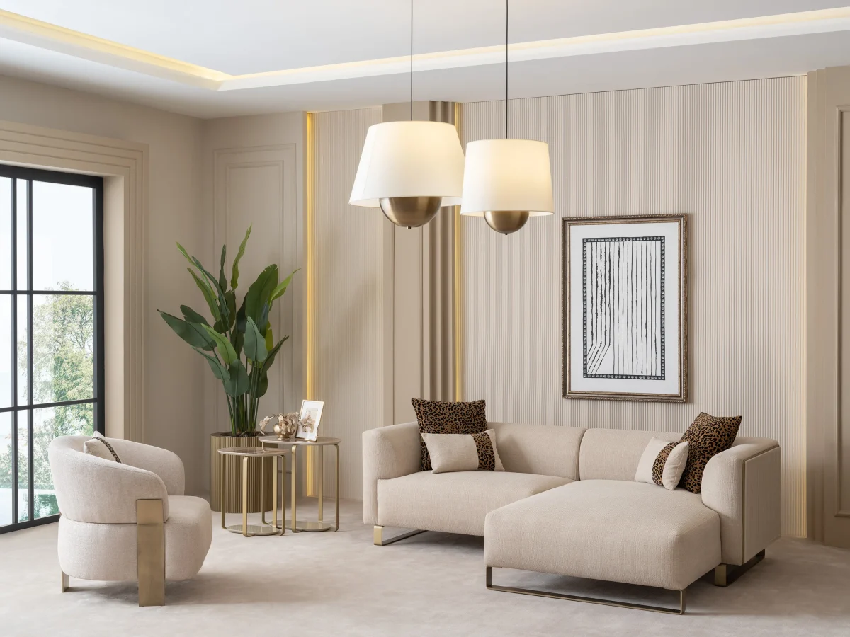 A luxurious modular Grandeur sofa set in a bright, modern living room. The set features cream-colored fabric upholstery with rectangular cushions and sleek gold metallic legs. Beside the modular sections sits a matching rounded armchair with gold accents. The scene includes minimalist decor, a marble coffee table, and large windows, highlighting the elegant design of the Grandeur furniture from Turkey.