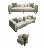 A luxurious modular Grandeur sofa set in a bright, modern living room. The set features cream-colored fabric upholstery with rectangular cushions and sleek gold metallic legs. Beside the modular sections sits a matching rounded armchair with gold accents. The scene includes minimalist decor, a marble coffee table, and large windows, highlighting the elegant design of the Grandeur furniture from Turkey.