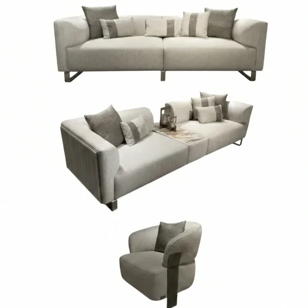 A luxurious modular Grandeur sofa set in a bright, modern living room. The set features cream-colored fabric upholstery with rectangular cushions and sleek gold metallic legs. Beside the modular sections sits a matching rounded armchair with gold accents. The scene includes minimalist decor, a marble coffee table, and large windows, highlighting the elegant design of the Grandeur furniture from Turkey.