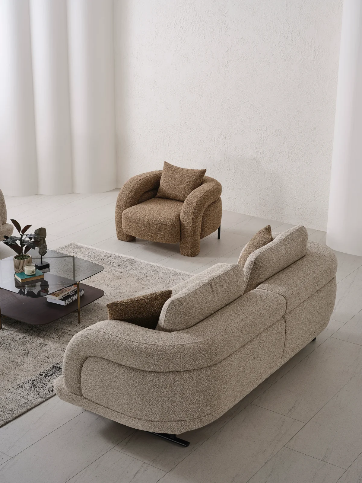 Modern fabric sofa set with rounded design, beige three-seater sofa and brown armchair, black metal legs, contemporary living room setting