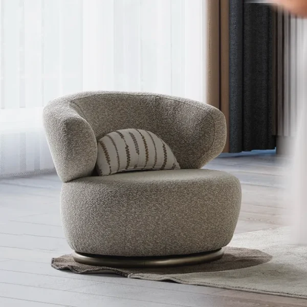 A modern Horizon Sofa set arranged in a chic living room. The furniture features textured grey upholstery with distinctive folded armrests and sleek champagne gold metallic legs. A matching round swivel armchair and a white coffee table with a cylindrical pouf complete the contemporary Turkish furniture ensemble.