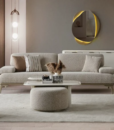 A modern Horizon Sofa set arranged in a chic living room. The furniture features textured grey upholstery with distinctive folded armrests and sleek champagne gold metallic legs. A matching round swivel armchair and a white coffee table with a cylindrical pouf complete the contemporary Turkish furniture ensemble.