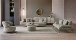 A modern Horizon Sofa set arranged in a chic living room. The furniture features textured grey upholstery with distinctive folded armrests and sleek champagne gold metallic legs. A matching round swivel armchair and a white coffee table with a cylindrical pouf complete the contemporary Turkish furniture ensemble.