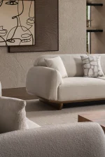 Modern rounded sofa with white boucle fabric and wooden base, luxury turkish furniture.