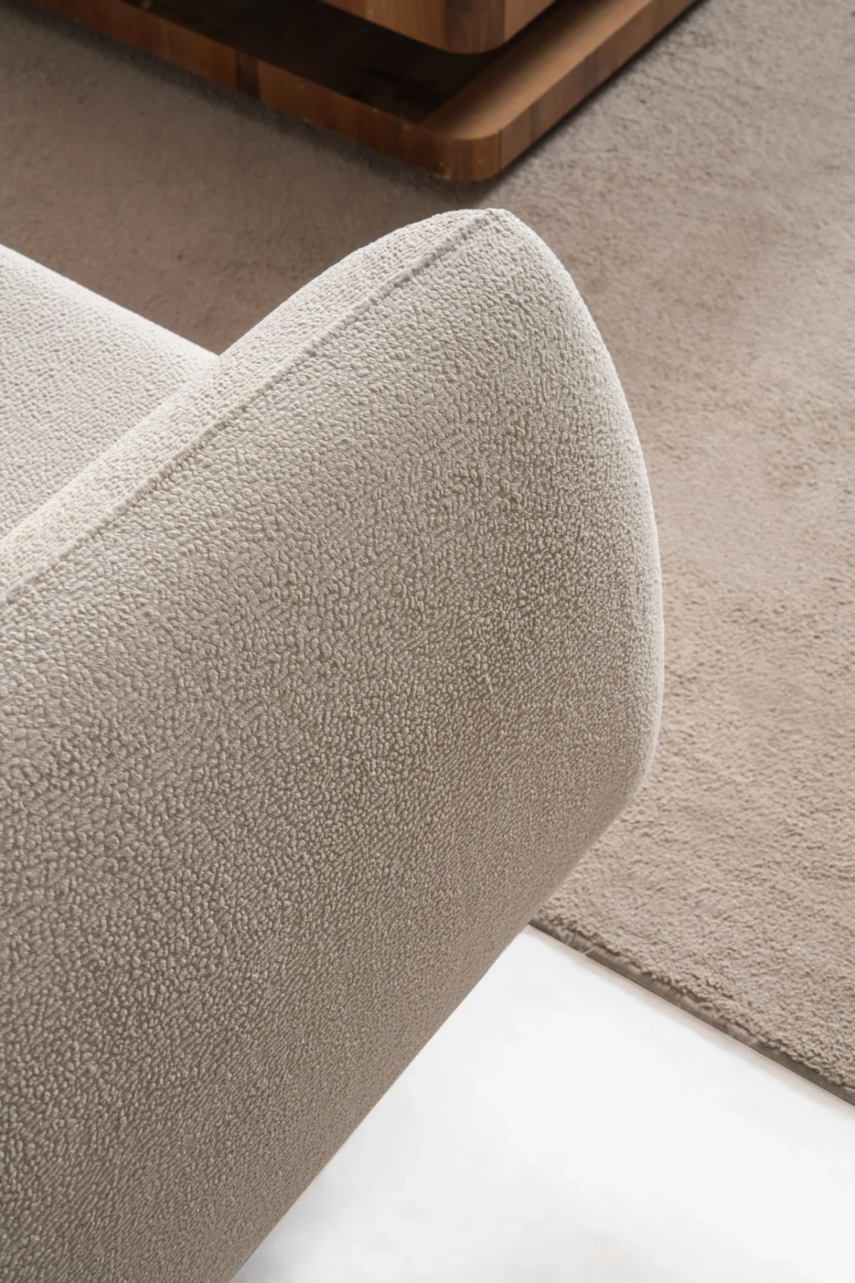 Modern rounded sofa with white boucle fabric and wooden base, luxury turkish furniture.