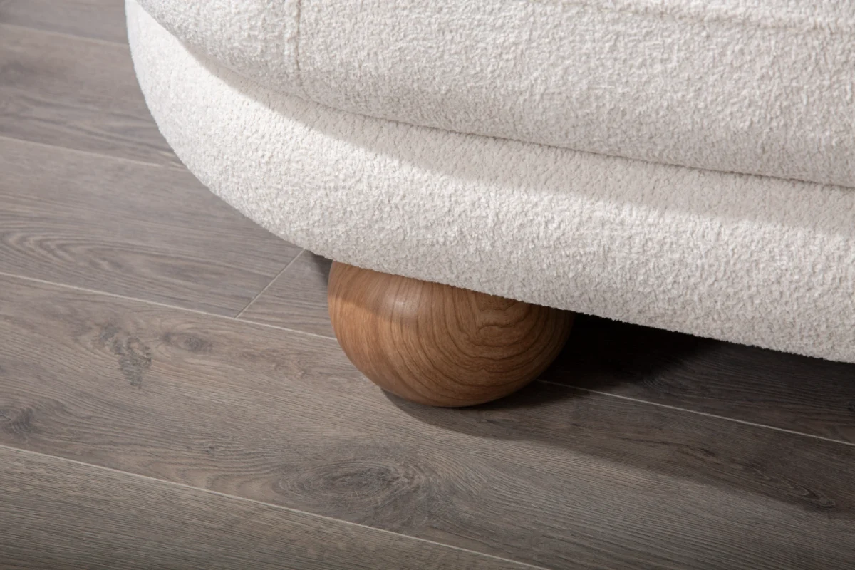 Premium sand grey curved sofa with sculptural round wooden legs and decorative cushions