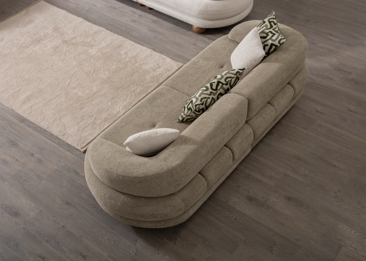 Premium sand grey curved sofa with sculptural round wooden legs and decorative cushions