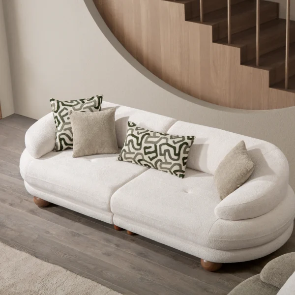 Premium sand grey curved sofa with sculptural round wooden legs and decorative cushions