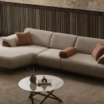 Loria Chaise Corner Sofa – 3 Modules three-piece modern beige sectional sofa featuring an extended chaise lounge, warm wooden arm details, terracotta accent pillows, and dark wooden legs.