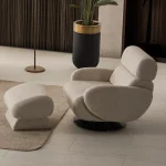Loria Armchair modern beige swivel armchair featuring textured fabric upholstery, rounded armrests, high back neck support, and a black circular base.
