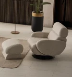 Loria Armchair modern beige swivel armchair featuring textured fabric upholstery, rounded armrests, high back neck support, and a black circular base.