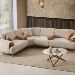 Loria Corner Sofa – 4 Modules four-piece sectional sofa in light beige upholstery featuring wooden armrest details, terracotta bolster cushions, and natural wooden legs.