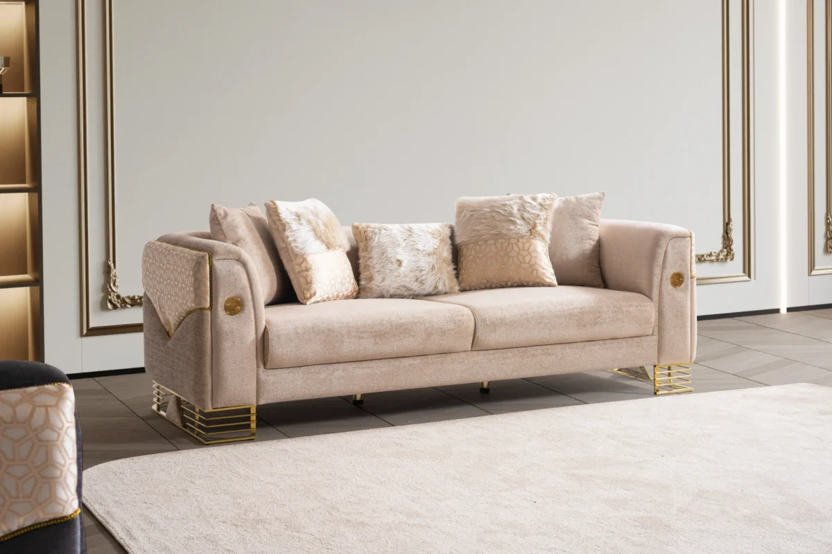 Luxia Sofa Set featuring a charcoal velvet three-seater, a blush pink loveseat with geometric patterns, and matching armchairs. The set is detailed with gold-toned metal bases and frames, set in a neoclassical room with arched windows and ornate wall moldings.