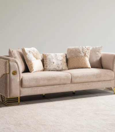 Luxia Sofa Set featuring a charcoal velvet three-seater, a blush pink loveseat with geometric patterns, and matching armchairs. The set is detailed with gold-toned metal bases and frames, set in a neoclassical room with arched windows and ornate wall moldings.