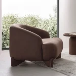 The distinguished Mirae Armchair in a bright, modern interior with curved architectural details and warm wooden accents, embodying a sense of balance and harmony.