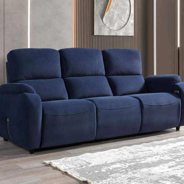 A modern three-seater reclining sofa featuring generous pillow-top backrests, wide padded armrests, and smooth plush upholstery set against a contemporary interior wall.