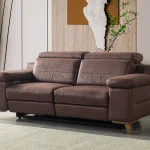A modern multi-seater recliner sofa featuring adjustable headrests, extendable footrests, wide plush armrests, and a rich textured leatherette finish in a contemporary living room setting.