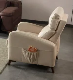 A high-back recliner-style accent armchair with soft neutral upholstery, cushioned head support, integrated side storage pocket, and dark tapered wooden legs, shown in a modern interior setting.