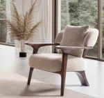 Sola Armchair with an exposed wooden frame, smooth wooden armrests, and a curved cushioned backrest