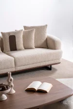 Sola Sofa featuring rounded armrests, plush back cushions, and a wooden base trim in a modern living room setting.