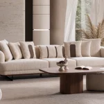 Sola Three Seater Sofa featuring rounded armrests, plush back cushions, and a wooden base trim in a modern living room setting.