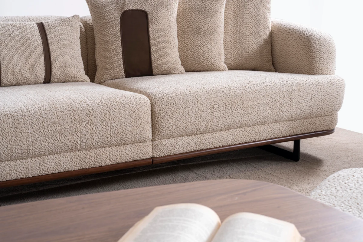 Sola Two Seater Sofa featuring rounded armrests, plush back cushions, and a wooden base trim in a modern living room setting.