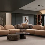 Tolia Corner Sofa - 5 Modules five-piece modular curved corner sofa featuring warm beige seating, patterned accent cushions, and an integrated wooden console table.
