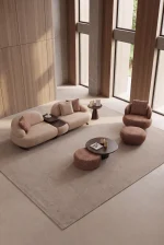 Tolia Set featuring a modular curved sofa, sculptural armchair, matching ottomans, and coffee tables arranged on a large round patterned rug in a modern living room.