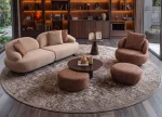 Tolia Sofa Set featuring a modular curved sofa, sculptural armchair, matching ottomans, and coffee tables arranged on a large round patterned rug in a modern living room.