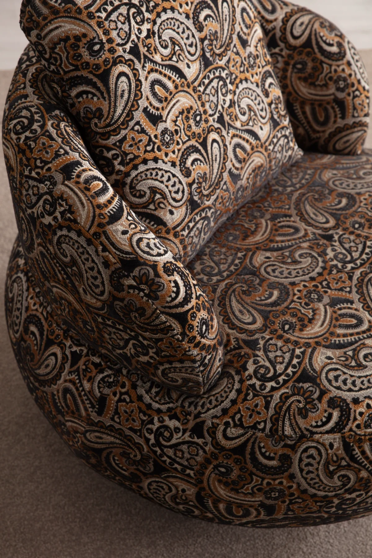 Tolia Armchair sculptured round swivel armchair featuring intricate paisley pattern upholstery and a plush back cushion.