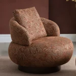 Tolia Armchair sculptured round swivel armchair featuring intricate paisley pattern upholstery and a plush back cushion.