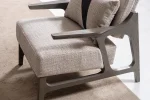 A contemporary accent armchair featuring an architectural open wooden frame, slim contoured armrests, a deep plush seat cushion, and a matching geometric accent pillow in a sunlit room setting.